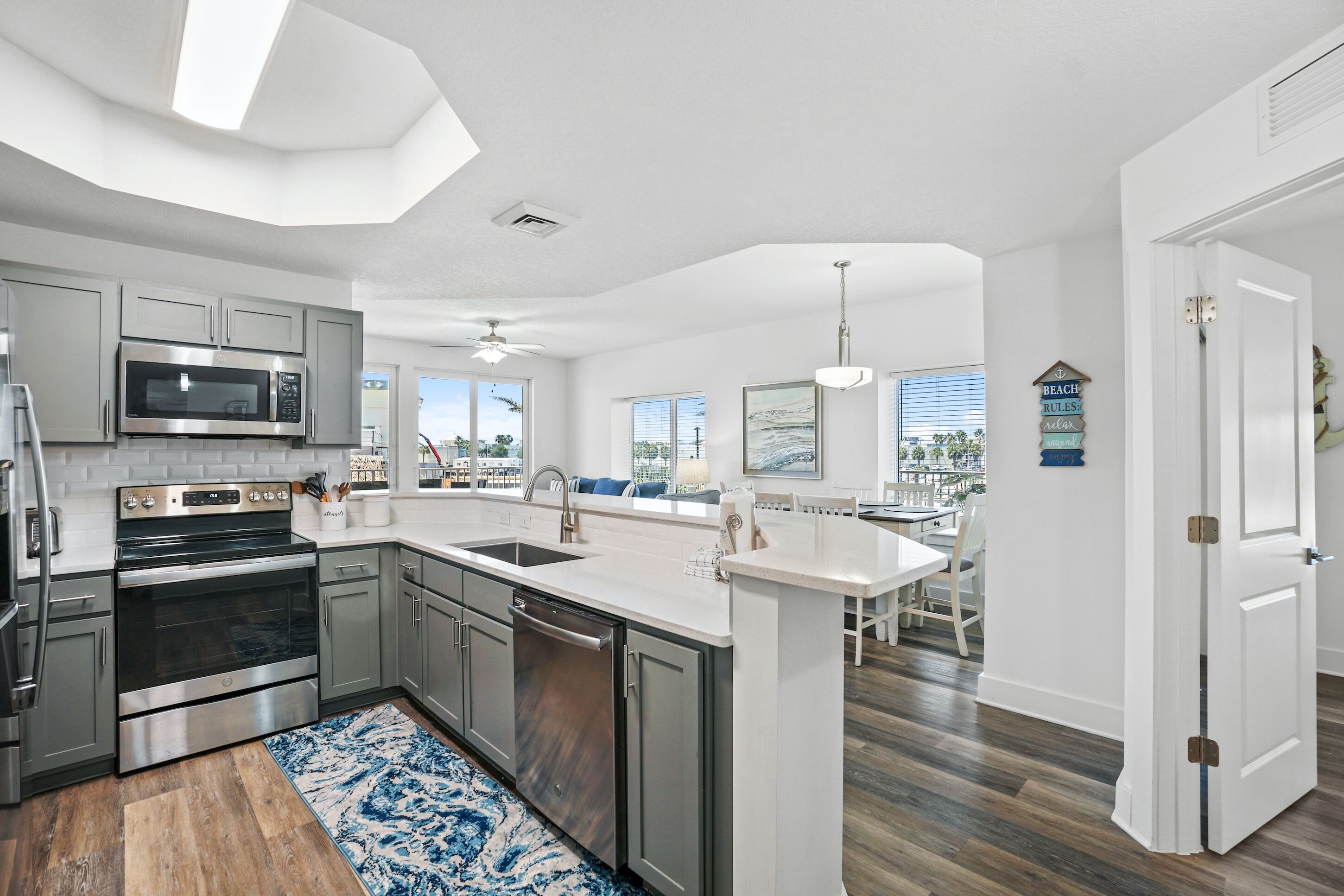A modern kitchen with stainless steel appliances, a central island, and a dining area with a view.
