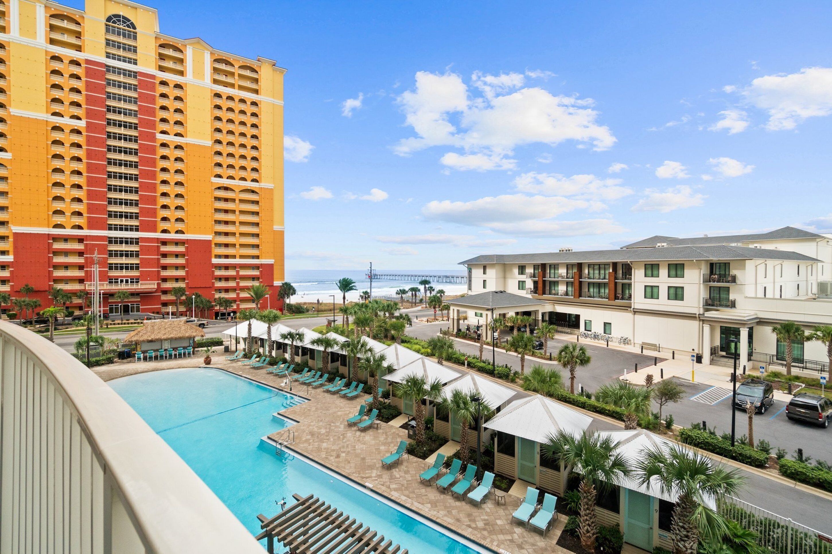 A hotel with a pool area, a beach view, and a parking lot.