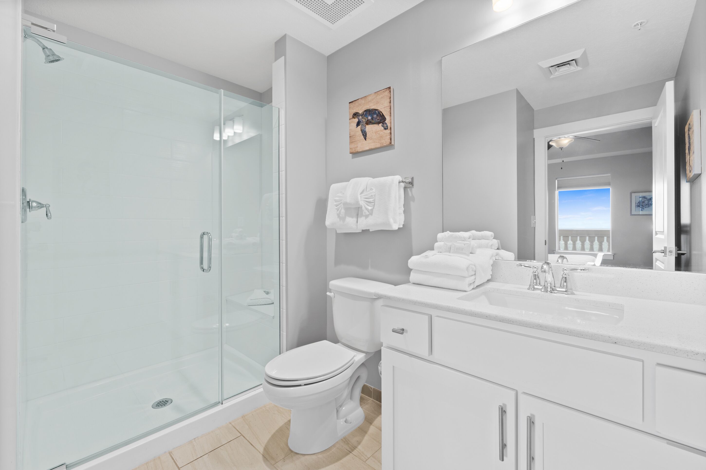 Een moderne badkamer met een glazen douchecabine, een wit toilet en een wastafel met spiegel.