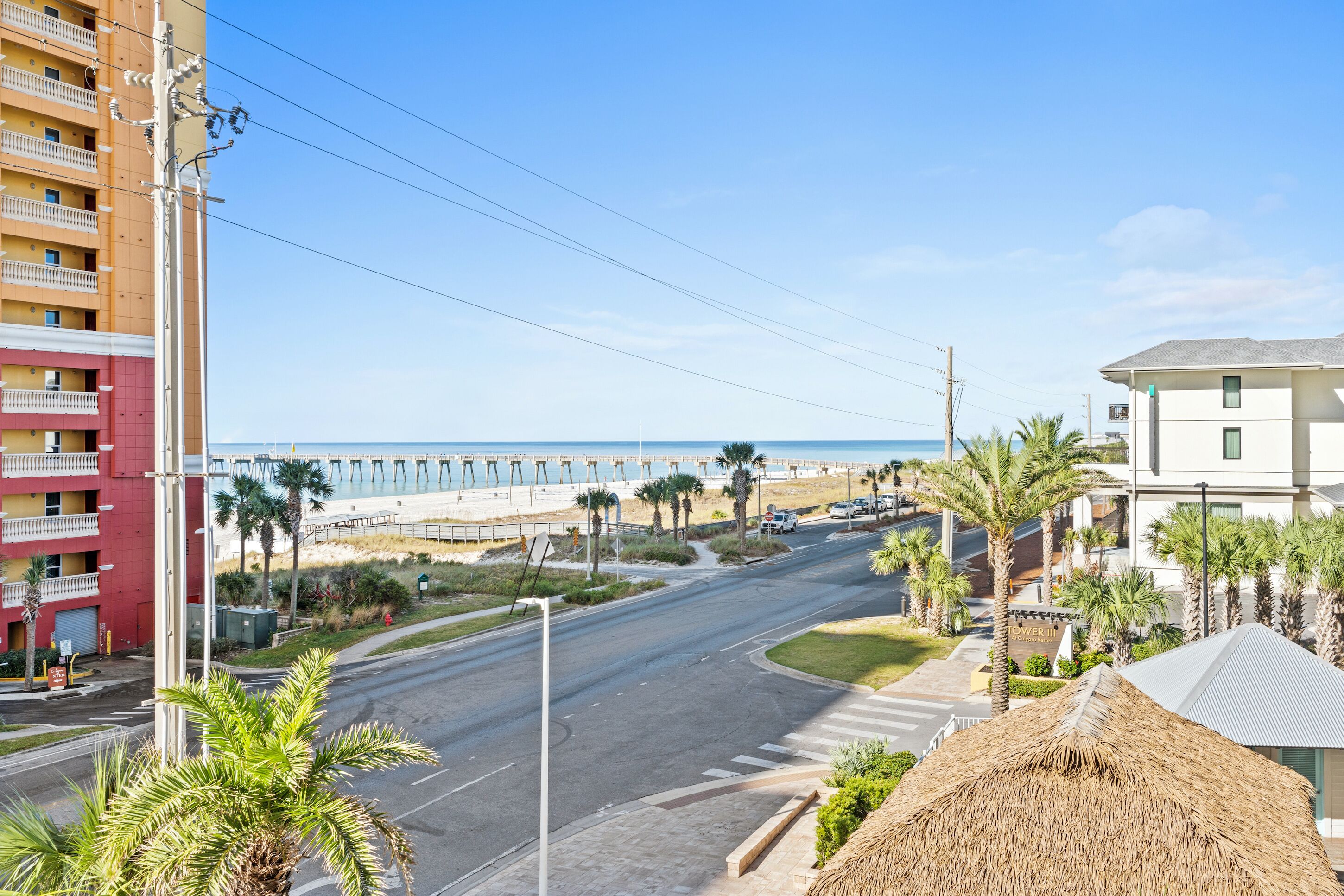 A coastal road with a beach and buildings in the background.