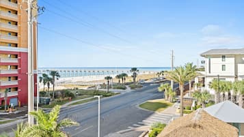 A coastal road with a beach and buildings in the background.