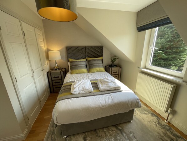 A bedroom with a bed, bedside tables, a lamp, a window, and a radiator.