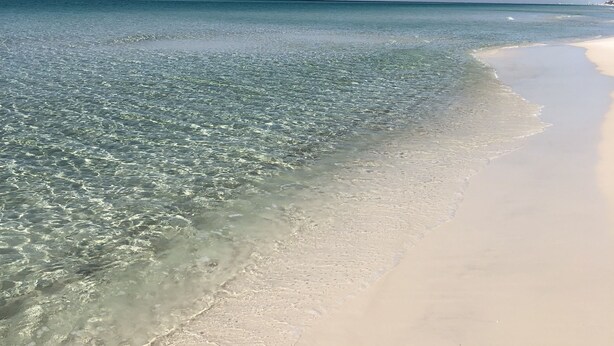 Une plage avec une eau claire et peu profonde et un rivage sablonneux.