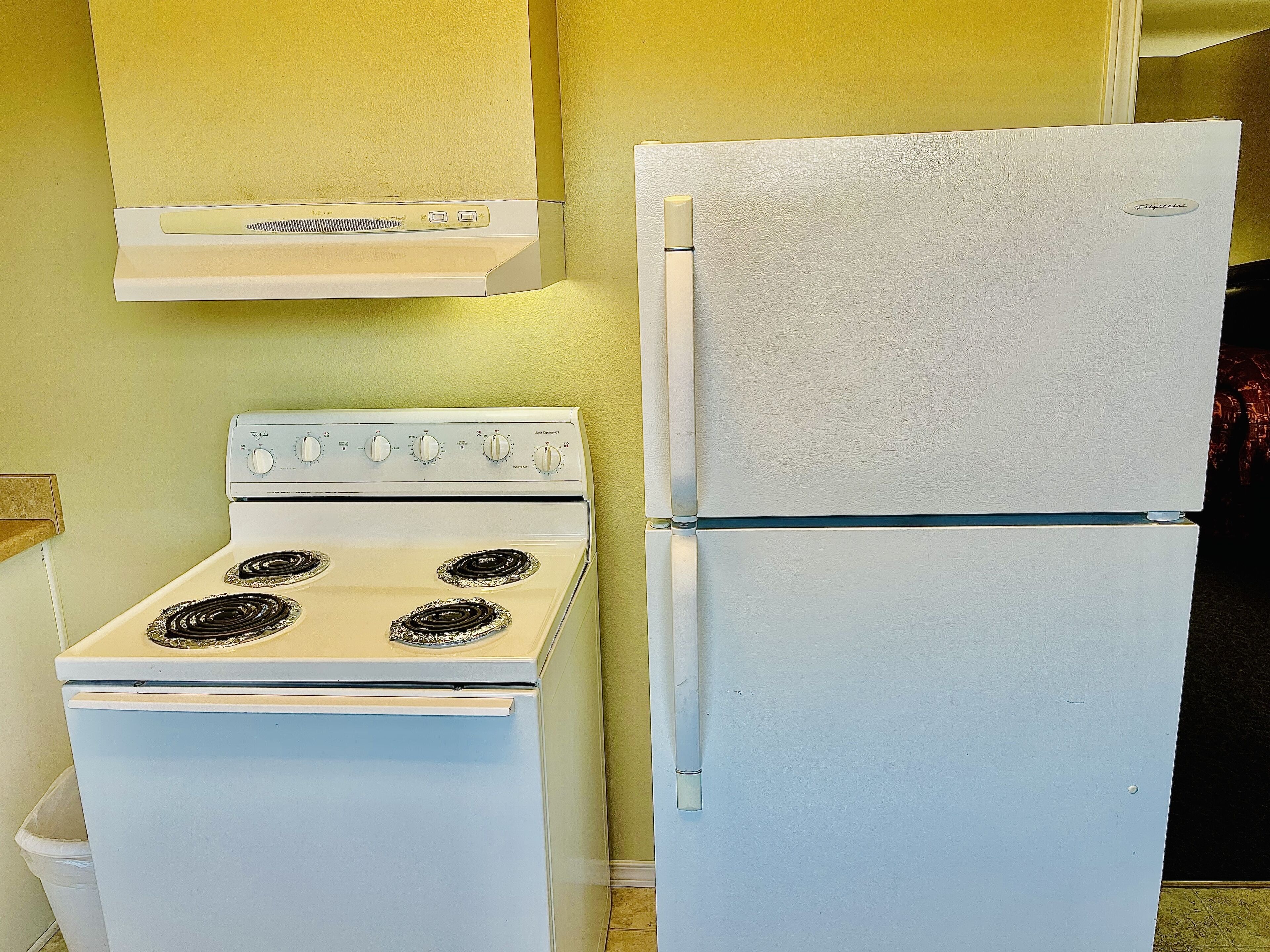 A kitchen with a white stove and refrigerator.