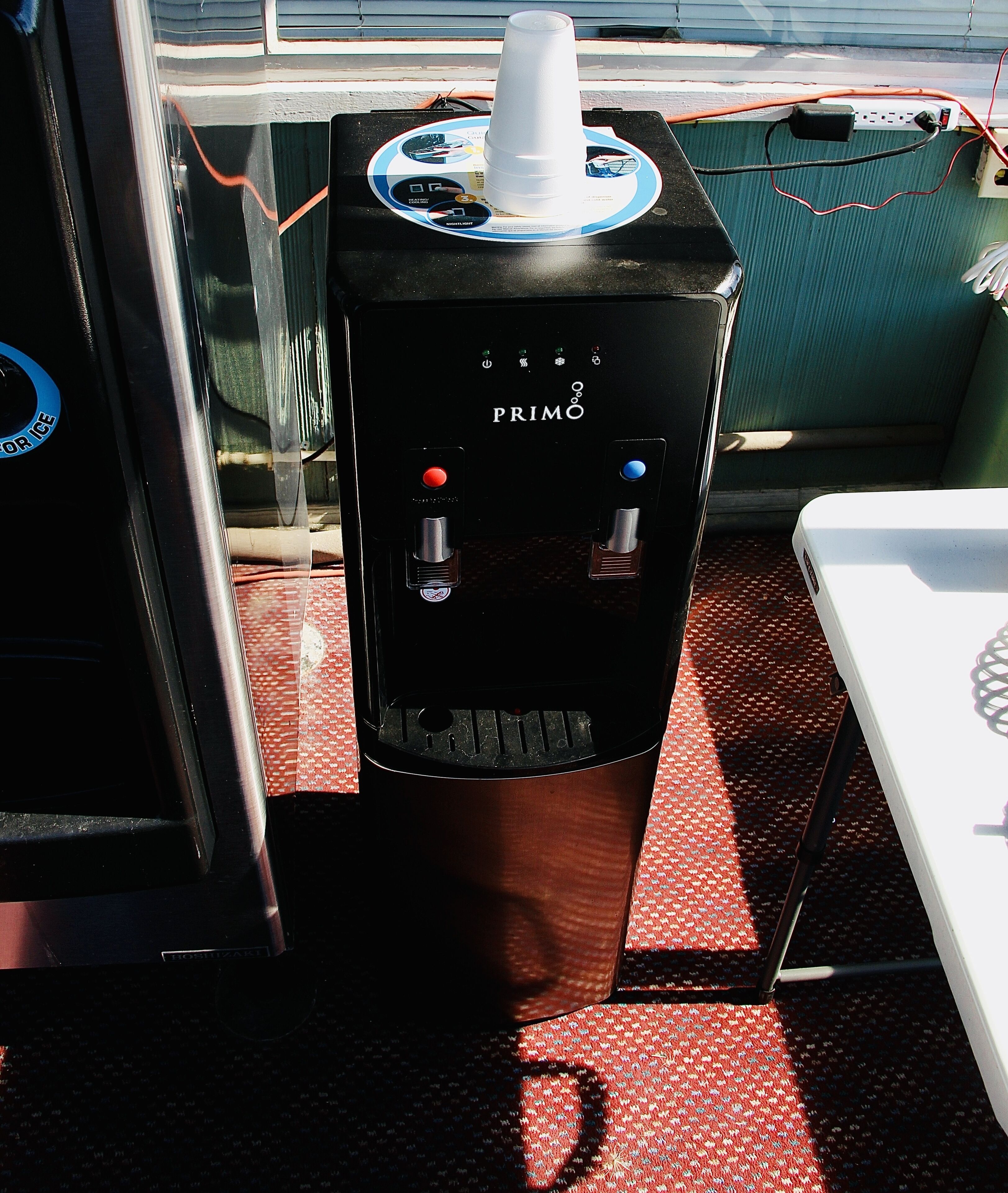 A water dispenser with two drink options, a cup holder, and a control panel on a boat deck.