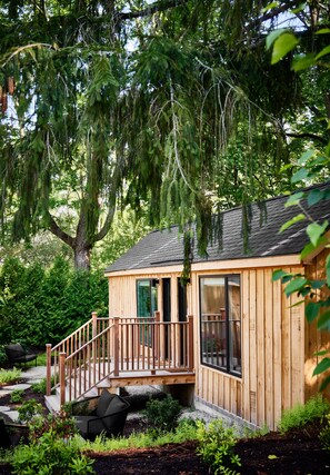A wooden cabin with a deck, surrounded by lush greenery and trees. - AWOL Kennebunkport (Kennebunkport)
