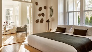 A bedroom with a large bed, a desk, and a chair. There are multiple windows providing natural light. - AWOL Kennebunkport (Kennebunkport)