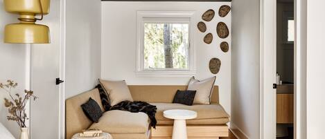 A modern living room with a sofa, a small round table, and a hanging light fixture.