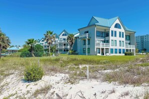 A beachfront hotel with multiple stories, balconies, and a pool area.