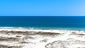 Una playa con cielo azul despejado, orilla de arena y algunas sombrillas.