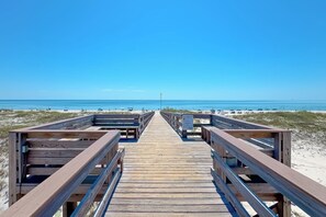 A wooden boardwalk leading to a beach with clear skies.