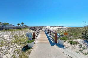 A wooden boardwalk leading to a beach with clear skies.