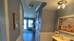 A hallway with a tiled floor, a cream-colored cabinet with drawers, and a painting on the wall.