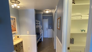 A narrow hallway with a bunk bed, a dresser, and a door leading to a room with a radiator.