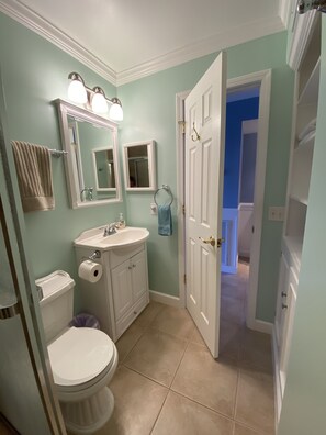 A bathroom with a toilet, sink, and mirror. There is a towel rack with a towel hanging on it. The walls are painted light blue, and the floor is tiled. - Myrtle Beach Resort-Direct oceanfront- free waterpark/grills-Recently updated! (Myrtle Beach)