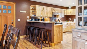 Eine Küche mit Holzausstattung, einer Bar mit Barhocker und einem freundlichen Willkommensschild.