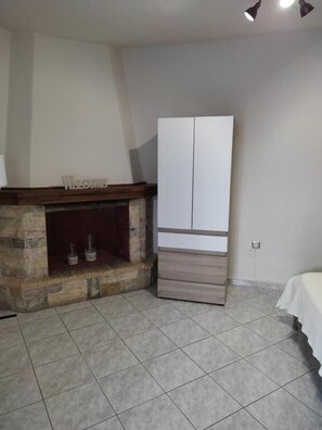 A room with a fireplace, a wardrobe, and a bed. - Garden Square Inn (Markopoulo Mesogaias)