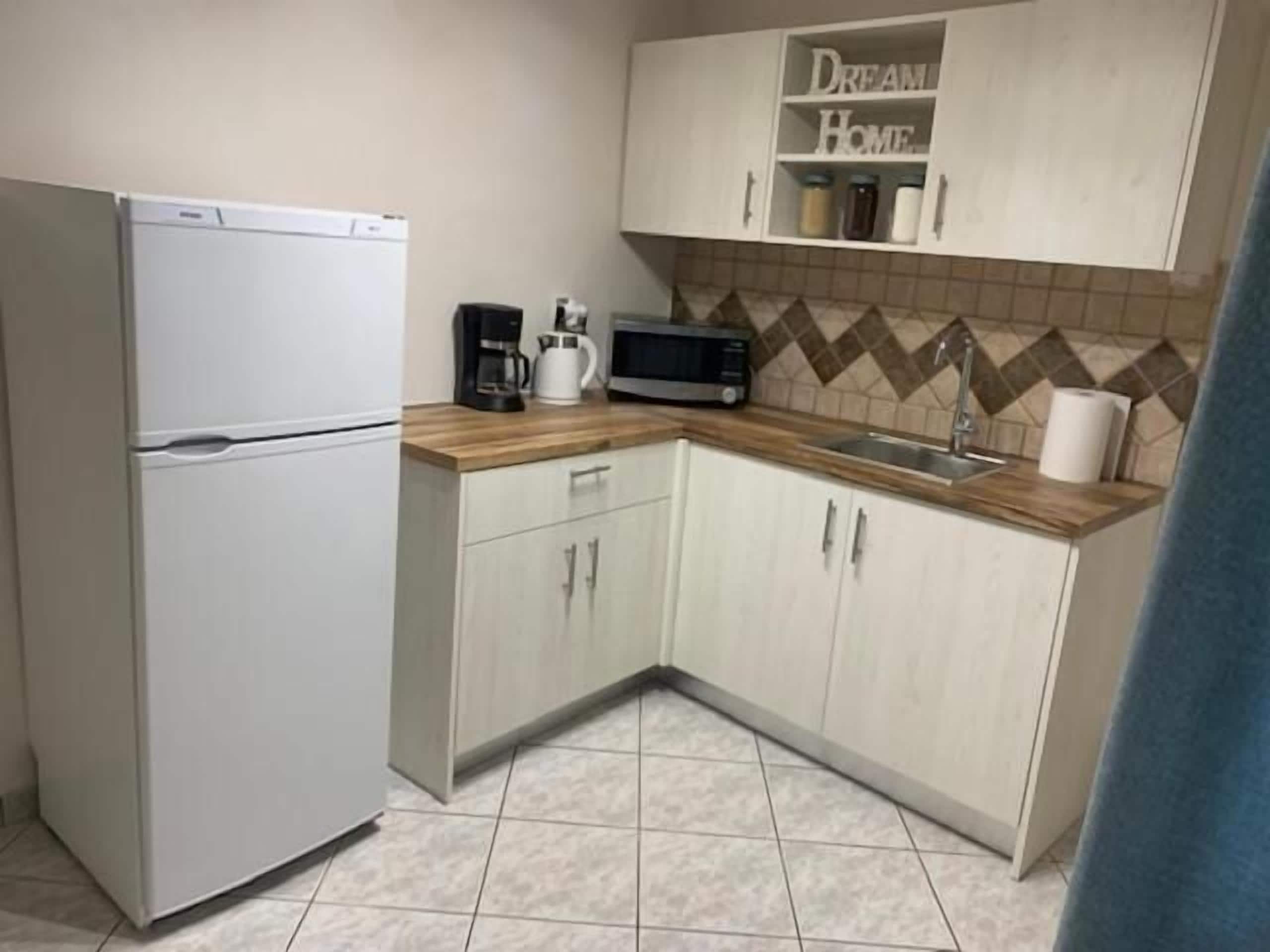 Cocina compacta equipada con refrigerador, microondas y cafetera.