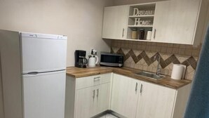 A compact kitchen with a refrigerator, microwave, and coffee maker. - Garden Square Inn (Markopoulo Mesogaias)