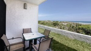 A patio with a table and chairs overlooking a beach. - Cozy Seaside Condo w/ Ocean Views - Pets Allowed! (St. Augustine)