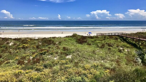A beach with a wooden boardwalk leading to the shore, sandy beach, and ocean. - Cozy Seaside Condo w/ Ocean Views - Pets Allowed! (St. Augustine)