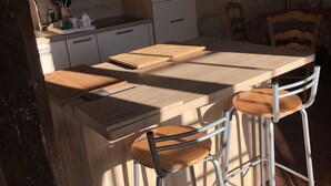 A compact kitchen with a wooden island, two bar stools, and a tiled backsplash.