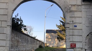 An old stone archway leading to a road, with a 'Propriété Privée' sign and a mailbox on the right.