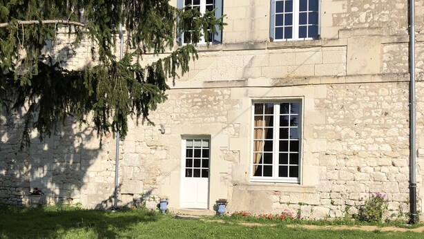 A stone building with a small front yard, a door, and windows.