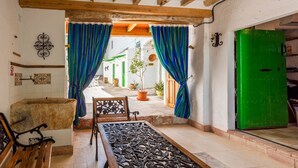 A room with a traditional wooden bench, a metal table with a floral pattern, and a green door. - Cortijo Don Simón Cabra by Ruralidays (Córdoba)