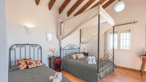 Une chambre à coucher avec deux lits, dont un lit à baldaquin, et une petite table de chevet avec une lampe.