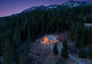 Eine Lodge mit Holzwandfassade, umgeben von dichtem Wald und Bergen.
