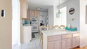 Una cocina moderna con armarios blancos, una isla central y un comedor con sillas.