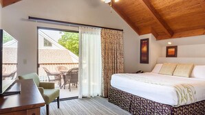 Ein Schlafzimmer mit einem Bett, einem Schreibtisch, einem Stuhl und Blick ins Freie.