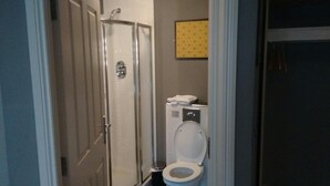 A small bathroom with a shower, toilet, and a towel rack. - Live Free, See Sofia - Premium Room 2 (Chilkiya)