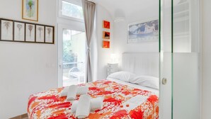 A hotel room with a bed, a window, a door, and wall decorations.