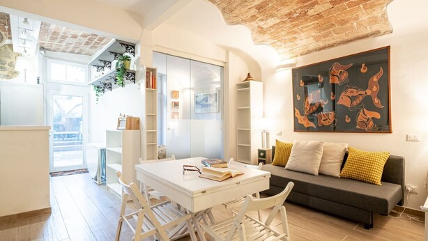 A modern living room with a white table, a grey sofa, and a large abstract painting.