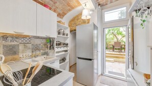 A kitchen with a modern design, including a built-in oven, a refrigerator, and a window leading to an outdoor patio.