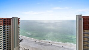 Ein Hochhaus mit Blick auf den Strand, das mehrere Balkone und einen Sandstrand im Vordergrund zeigt.