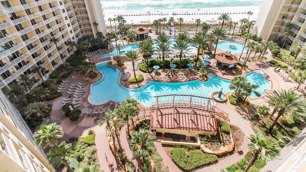 Ein Resort mit mehreren Schwimmbecken, Palmen und Blick auf den Strand.