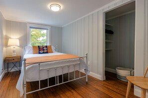 Une chambre à coucher avec un lit, une table de chevet, une fenêtre et un placard.