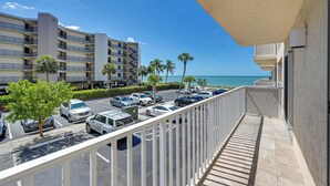 A hotel balcony with a view of the ocean and parked cars. - Oceanfront Bonita Beach Condo w/ Pool Access! (Bonita Springs)