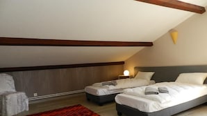 Ein Schlafzimmer mit zwei Betten, einem roten Teppich mit Muster und einem Holzbalken an der Decke.