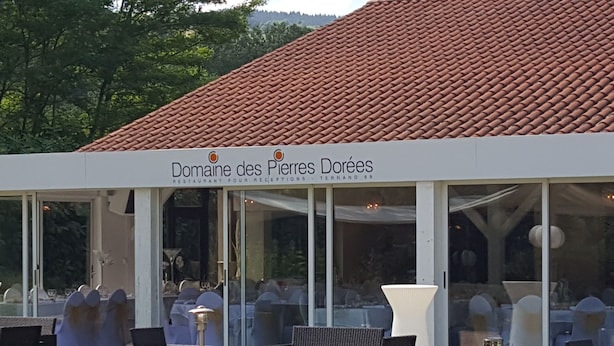 Ein Restaurant namens Domaine des Pierres Dorées mit Außenbereich und einem roten Ziegeldach.