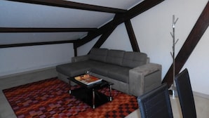 Ein Loft-Zimmer mit grauem Sofa, einem gemusterten Teppich und einem modernen Couchtisch.