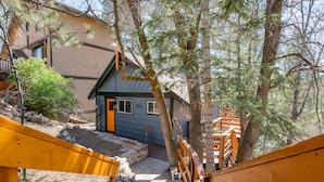 A wooden staircase leading to a house with a blue door, surrounded by trees and a rocky ground. - Forest Escape - Secluded Feeling, Forest Views, Fireplace, Deck (Fawnskin)