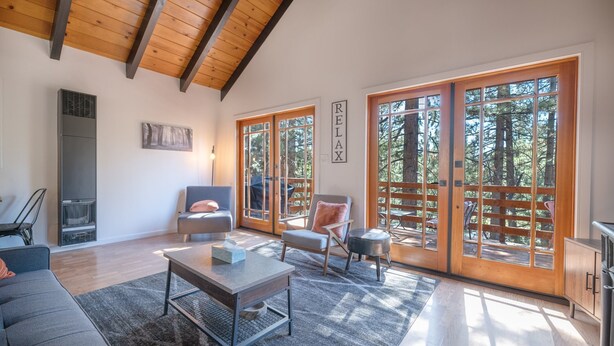 A spacious living room with a fireplace, large windows, and a 'RELAX' sign. - Forest Escape - Secluded Feeling, Forest Views, Fireplace, Deck (Fawnskin)
