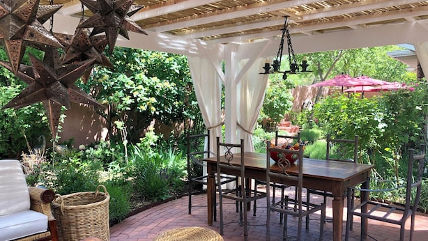 An outdoor patio with a wooden table, wicker chairs, and a hanging star decoration.