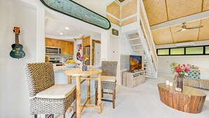 Un amplio espacio de sala con una mesa de comedor, sillas, una escalera y una cocina al fondo.