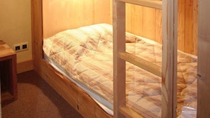 Habitación con literas, paredes de madera y una escalera.