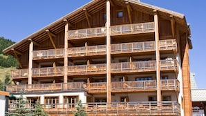 Un edificio de madera de varios pisos con balcones, probablemente un hotel o una posada, con un estilo arquitectónico alpino tradicional.